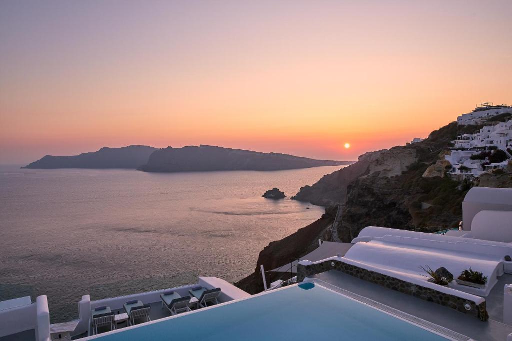 a sunset over the ocean on a cliff at La Perla Villas and Suites - Adults Only in Oia