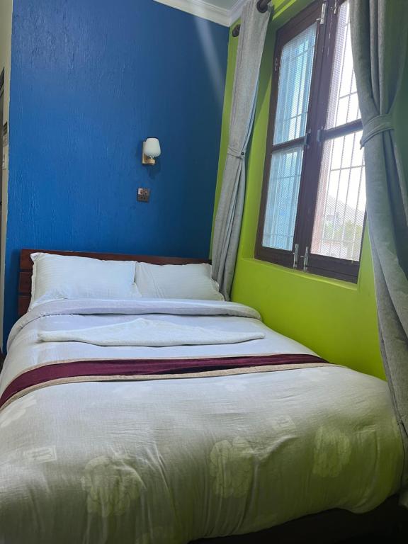 a bed in a blue room with a window at Bandipur Samira Homestay & Mountain View Restaurant in Bandīpur