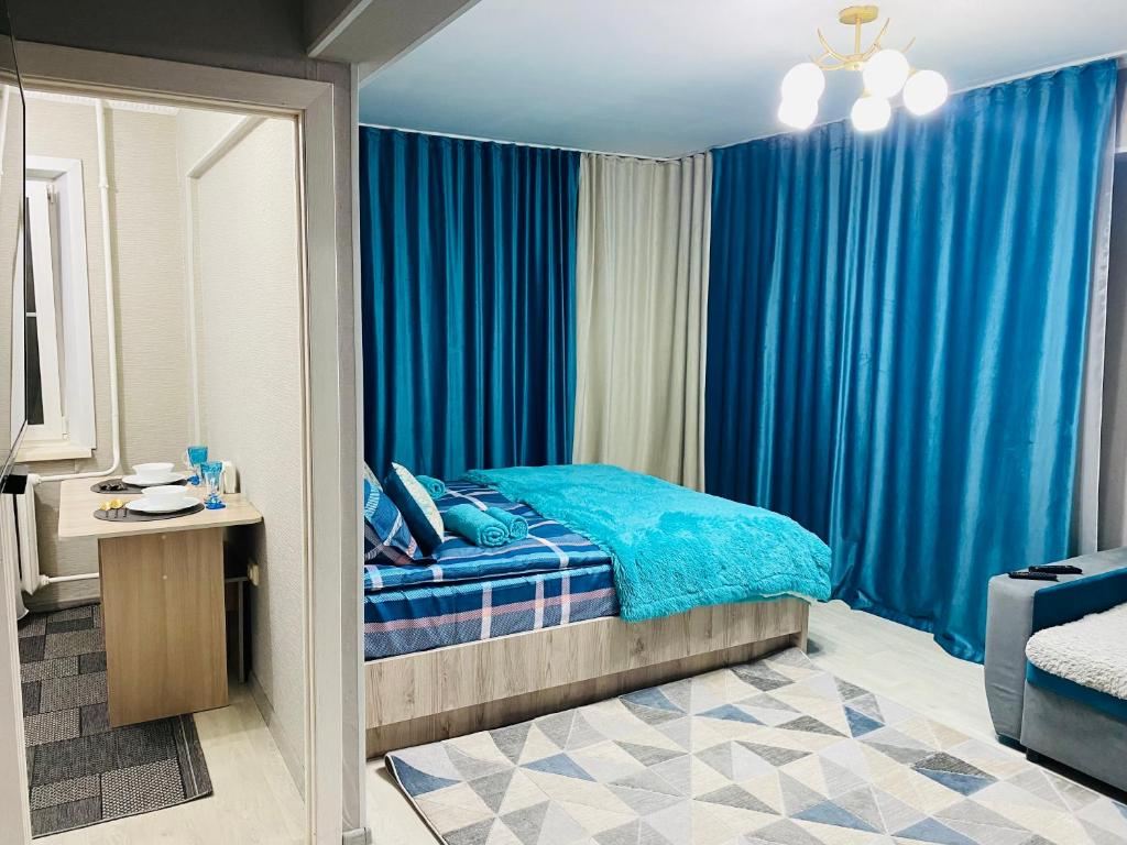 - une chambre avec un lit bleu et des rideaux bleus dans l'établissement Апартаменты на Бурова, à Öskemen