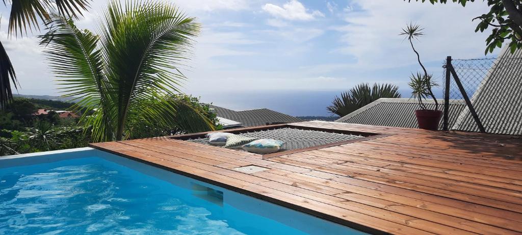 une terrasse en bois à côté d'une piscine dans l'établissement Bungalow cosy avec piscine surplombant l'océan, à Bellemène