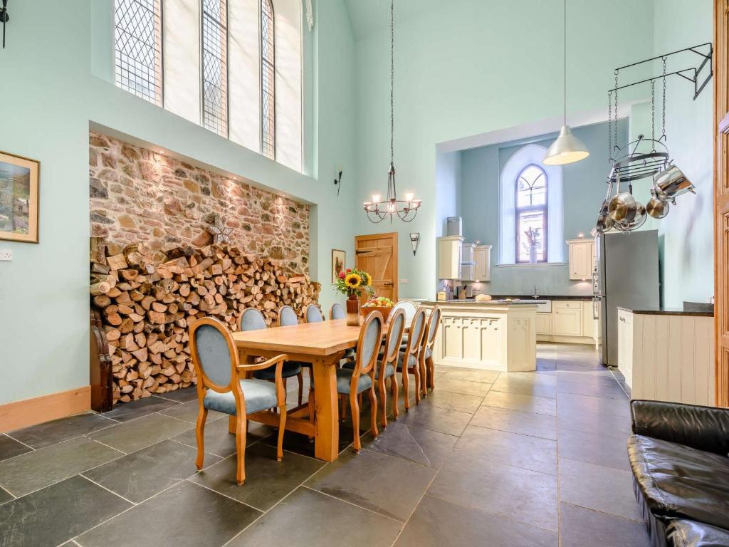 a dining room with a table and a pile of fire wood at 4 bed property in Isle of Bute 85215 in Kilchattan