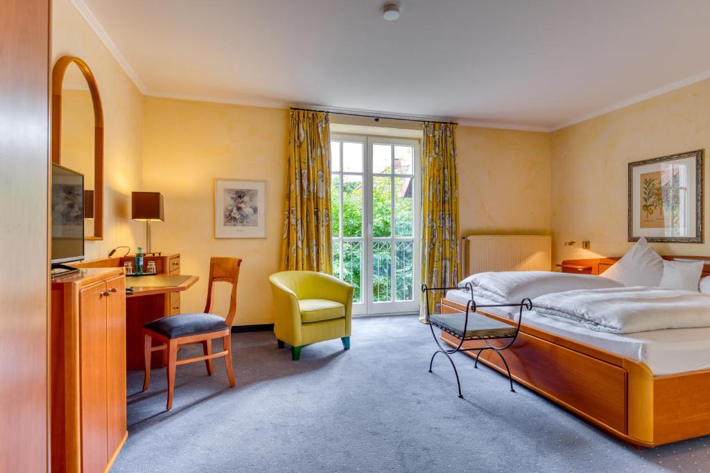 a bedroom with a bed and a desk and a chair at Hotel Alt Vellern in Beckum