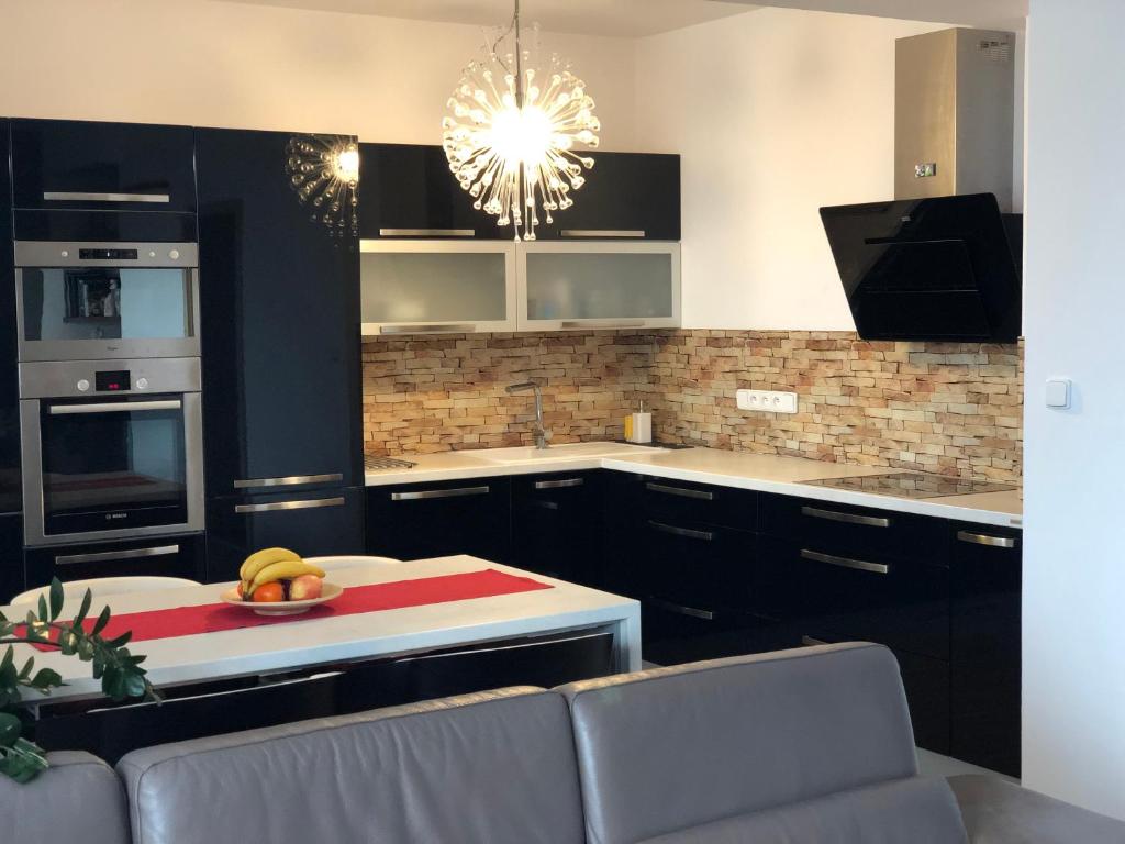 eine Küche mit schwarzen Schränken und einem Tisch mit Obst darauf in der Unterkunft Apartmán nearly SKI ARENA in Nové Město na Moravě