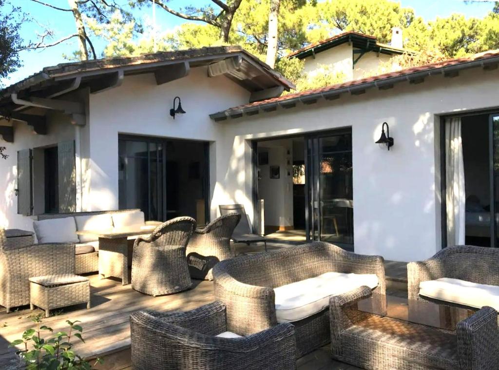- une terrasse avec des meubles en osier en face d'une maison dans l'établissement Moulleau - charmante maison 4 chambres et jardin privé, à La Teste-de-Buch