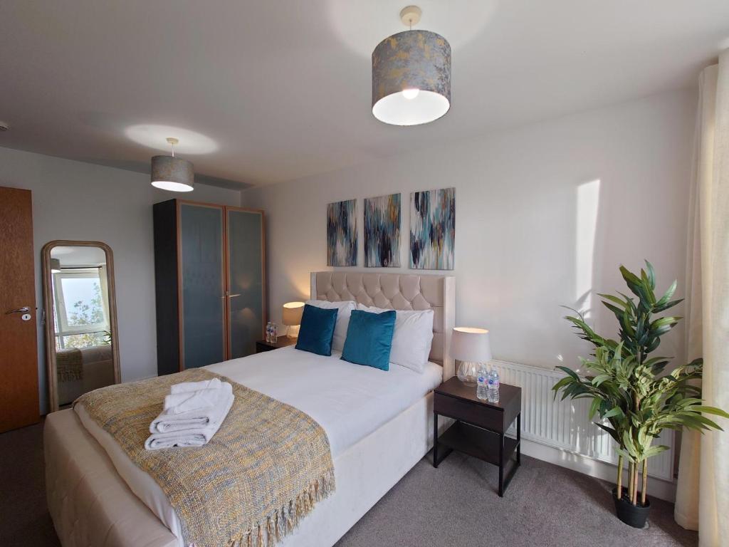 - une chambre avec un lit blanc et des oreillers bleus dans l'établissement Three Bed Serviced Apartment by London ExCeL, à Londres
