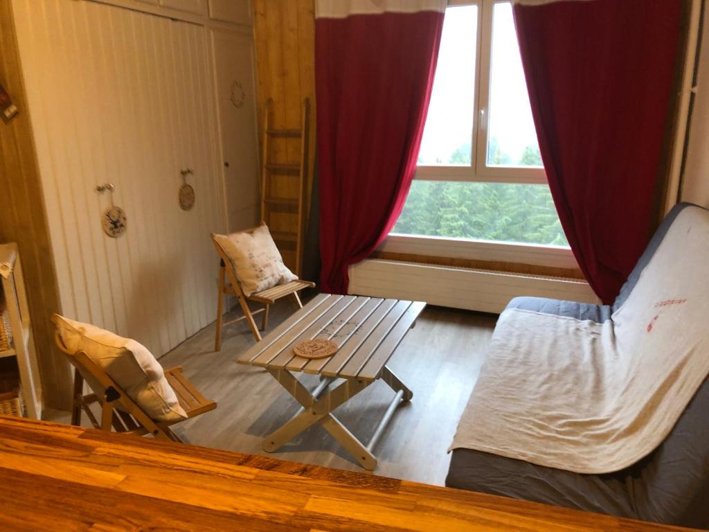 Habitación con cama, mesa y ventana en studio tout confort au pied des pistes du lioran en Laveissière