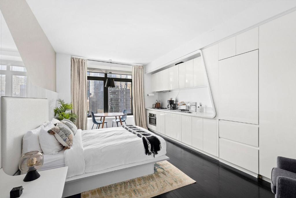 a white room with a bed and a kitchen at Financial District studio w WD gym elevator NYC-1359 in New York