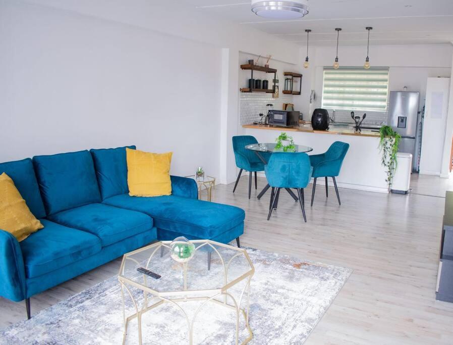 a living room with a blue couch and a table at 2 Bedroom Apartment with Modern Finishes Hill Tud Stays in Pietermaritzburg