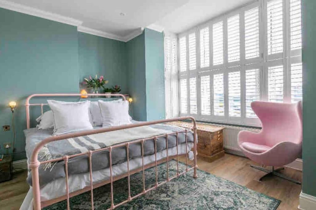 een slaapkamer met een metalen bed en een roze stoel bij Walpole View - Pet Friendly in Margate