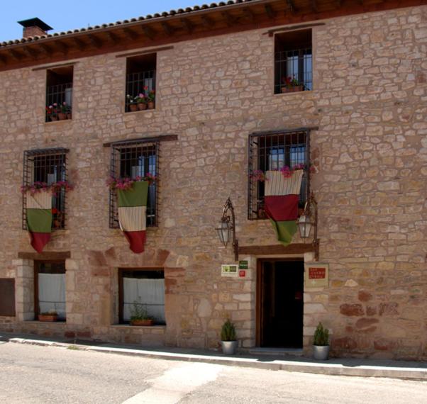 un bâtiment en briques avec des plantes en pot sur les fenêtres dans l'établissement Los Cuatro Caños, à Sigüenza