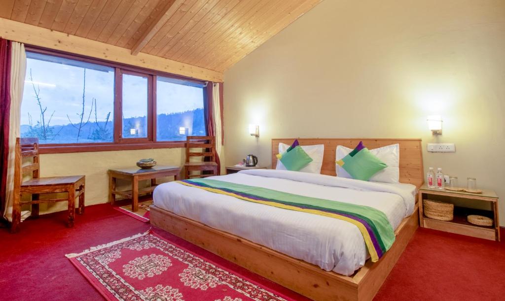 a bedroom with a large bed and a large window at Treebo Trend Daak Bangla Retreat With Mountain View in Shimla