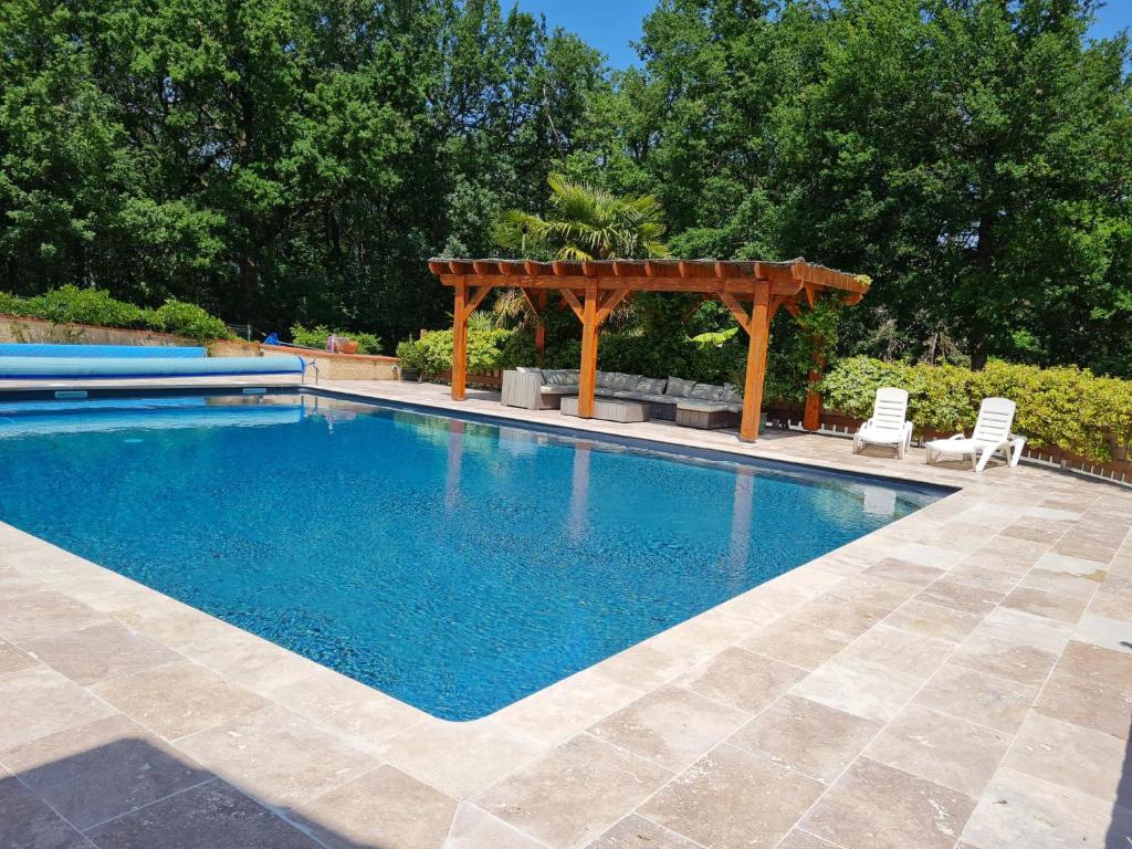 una piscina con pérgola de madera y sillas en Appartement Type F4, en Maurens