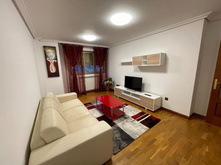 a living room with a white couch and a television at Bonito piso con aparcamiento a pie de la calle . in Nájera