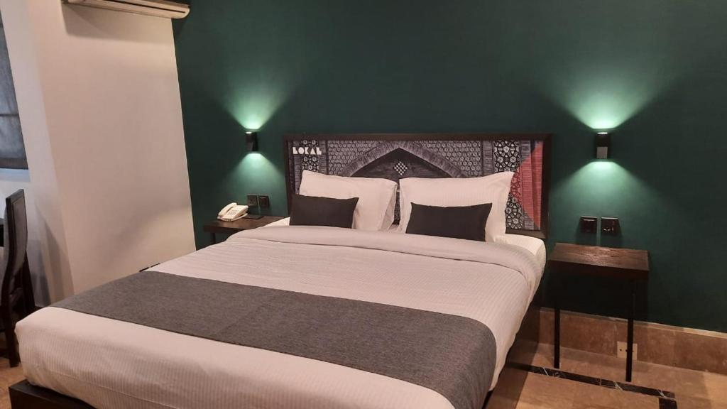 1 dormitorio con 1 cama grande y pared verde en LOKAL Rooms x Multan (City Center), en Multán