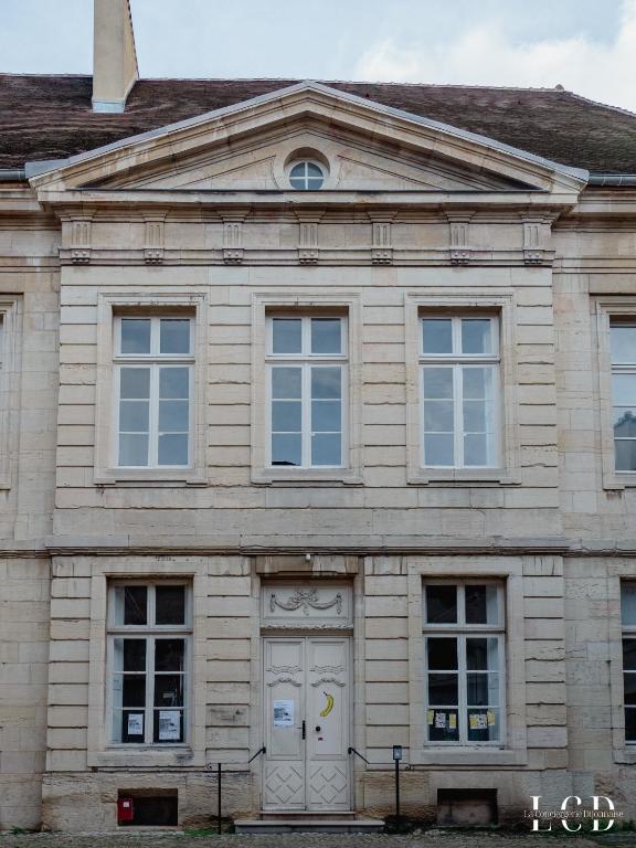 a stone building with a white door and windows at Le Buffon in Dijon