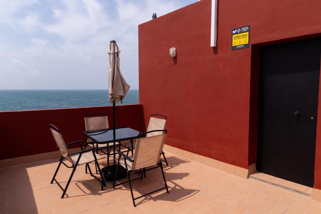 un patio con una mesa y una sombrilla y el océano en Casa completa triplex & parking by Gades Gestión, en Cádiz