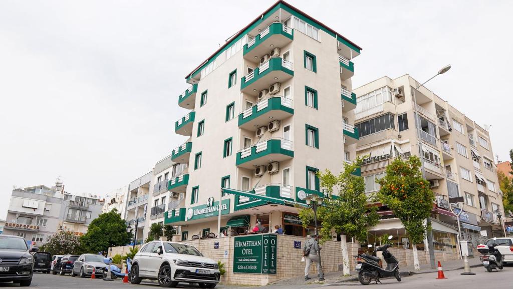 een hoog wit gebouw in een stadsstraat met auto's bij Hikmethan Otel in Kuşadası