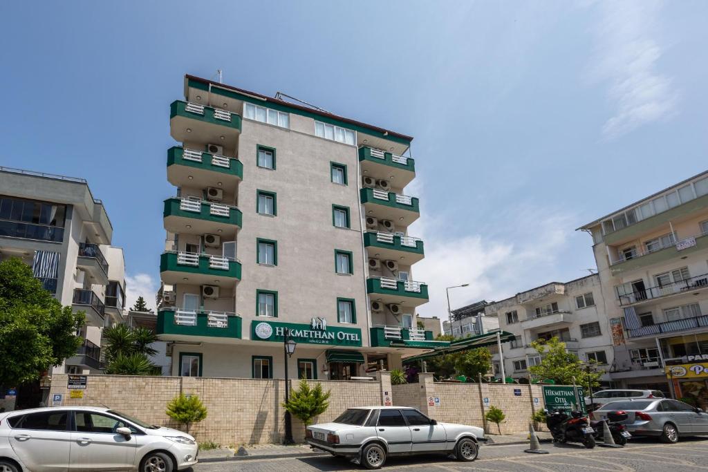 a tall building with cars parked in front of it at Hikmethan Otel in Kusadası