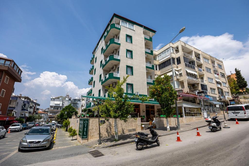 a building on a city street with cars and motorcycles at Hikmethan Otel in Kusadası