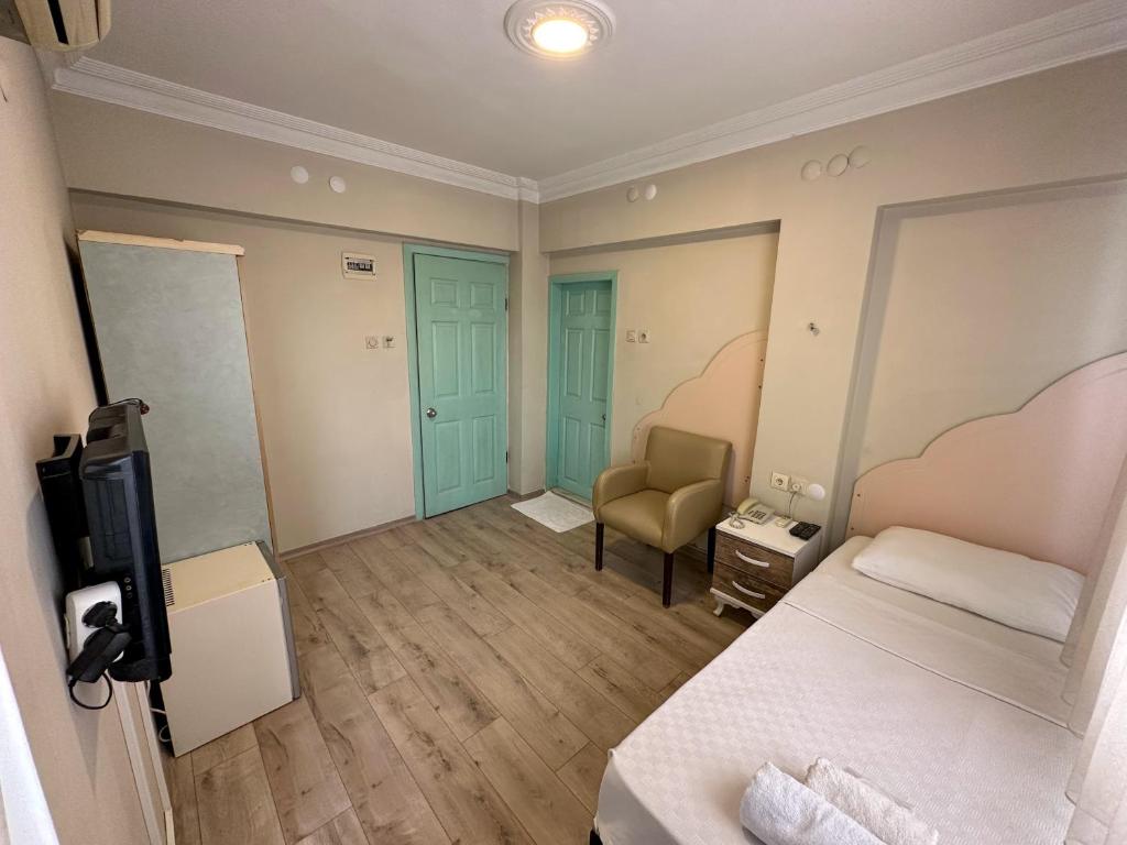 a bedroom with a bed and a chair and a television at Hikmethan Otel in Kusadası