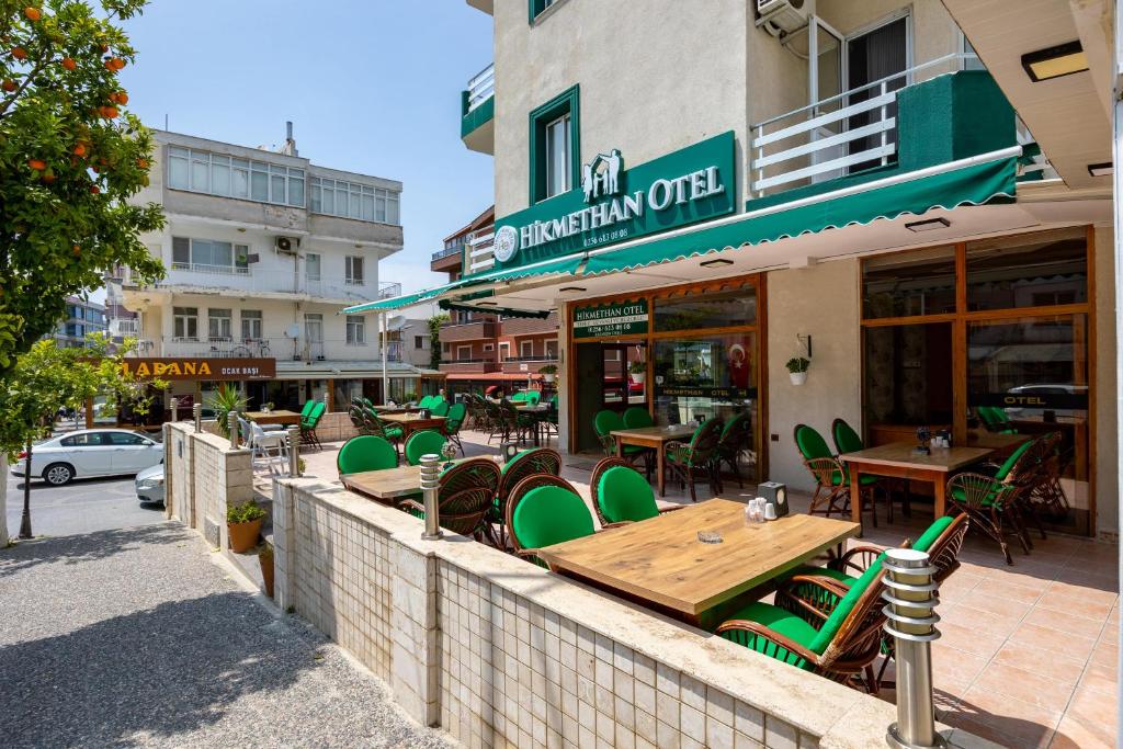 a restaurant with green chairs and tables on a street at Hikmethan Otel in Kusadası