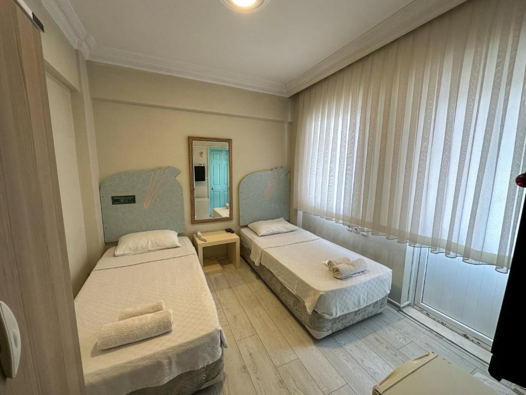a small room with two beds and a mirror at Hikmethan Otel in Kusadası