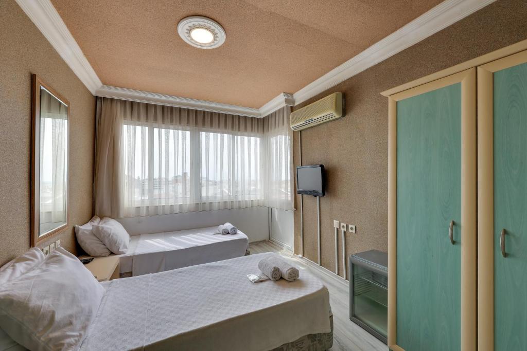 a hotel room with two beds and a window at Hikmethan Otel in Kusadası