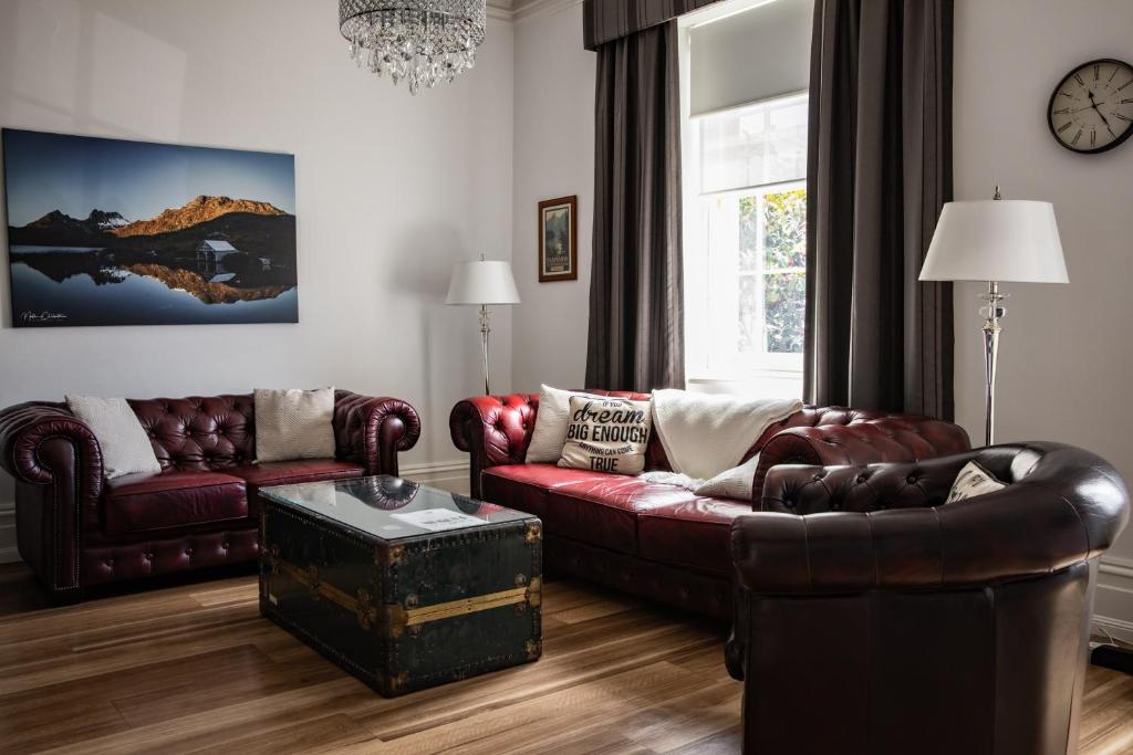 a living room with two leather couches and a table at Sanctum Boutique Apartments in Hobart