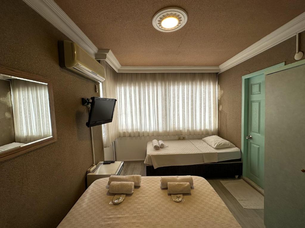 a small room with two beds and a television at Hikmethan Otel in Kusadası
