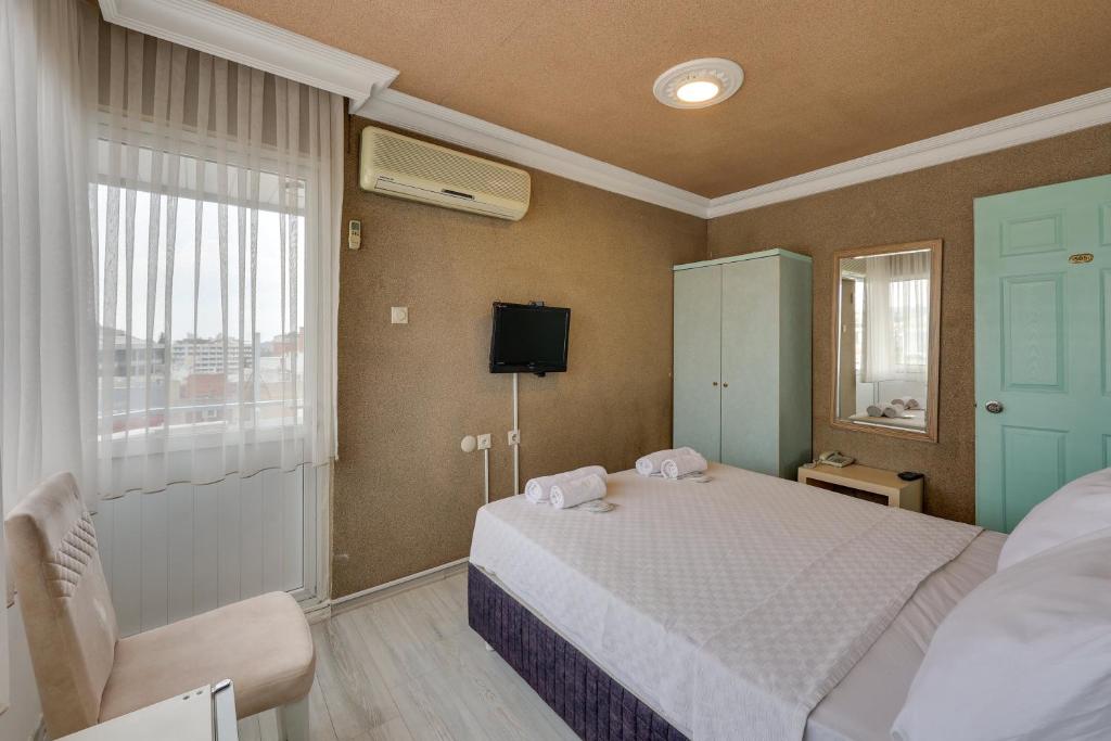 a bedroom with a bed and a tv and a window at Hikmethan Otel in Kusadası
