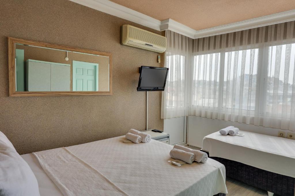 a hotel room with two beds and a tv at Hikmethan Otel in Kusadası