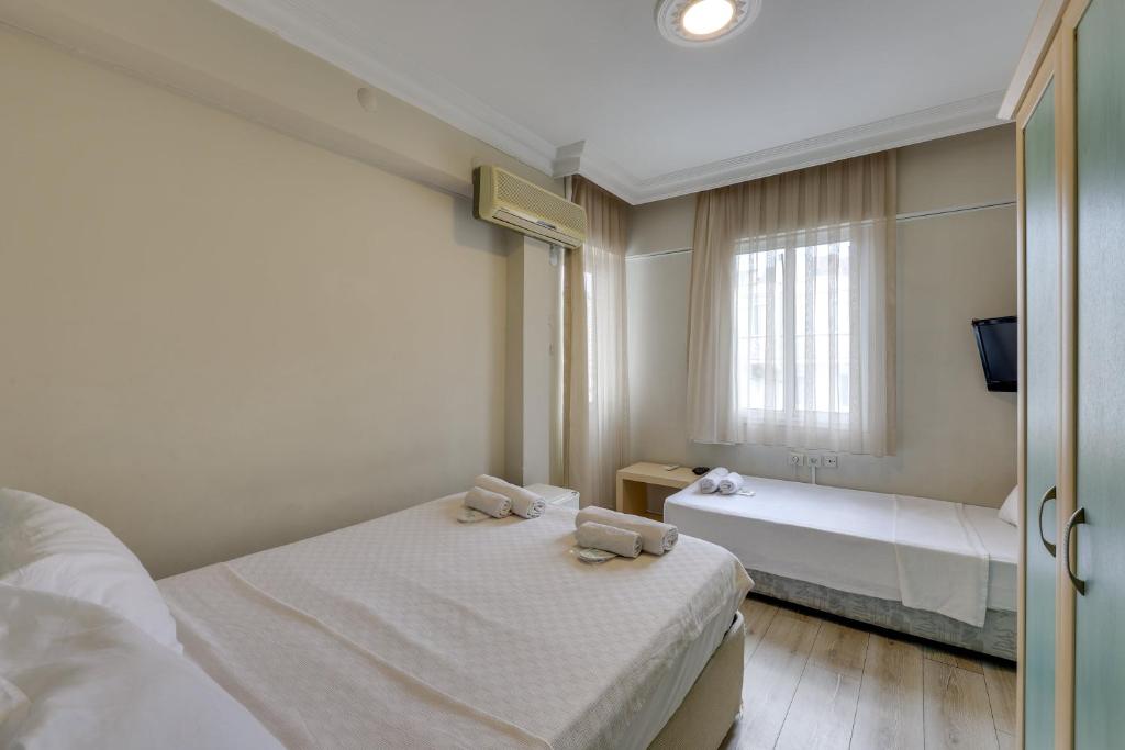 a bedroom with two beds and a window at Hikmethan Otel in Kusadası
