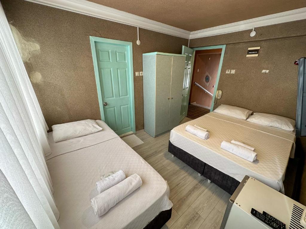 a room with two beds with towels on them at Hikmethan Otel in Kusadası