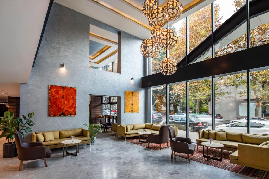 a lobby with couches and tables and windows at Tbilisi Saburtalo Hotel by Mercure in Tbilisi City