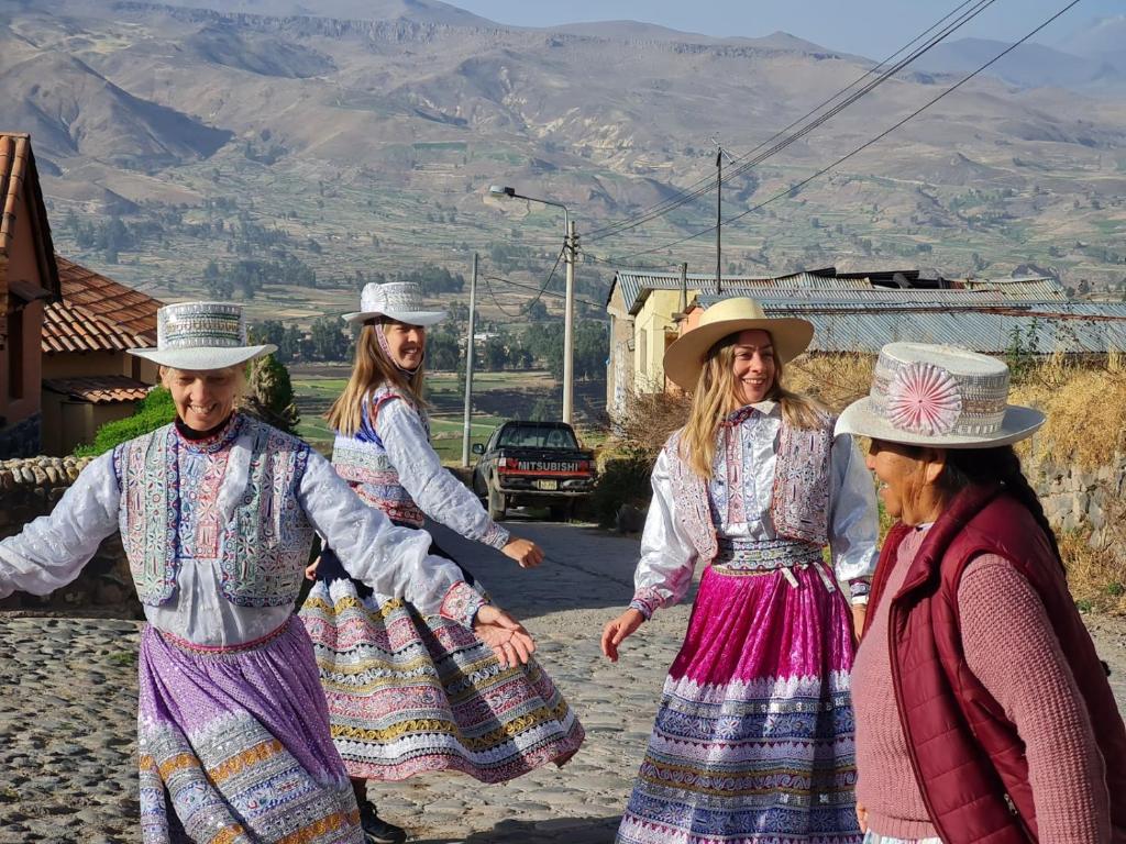 un grupo de personas con ropa tradicional caminando por una calle en Casa vivencial Mamá Vivi, en Coporaque