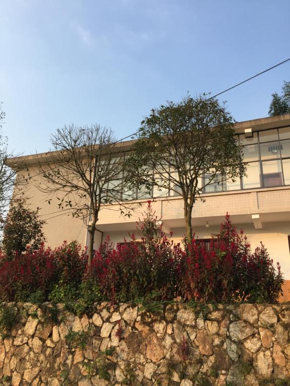 a building with trees and flowers in front of it at Youbao House in Xiangtan