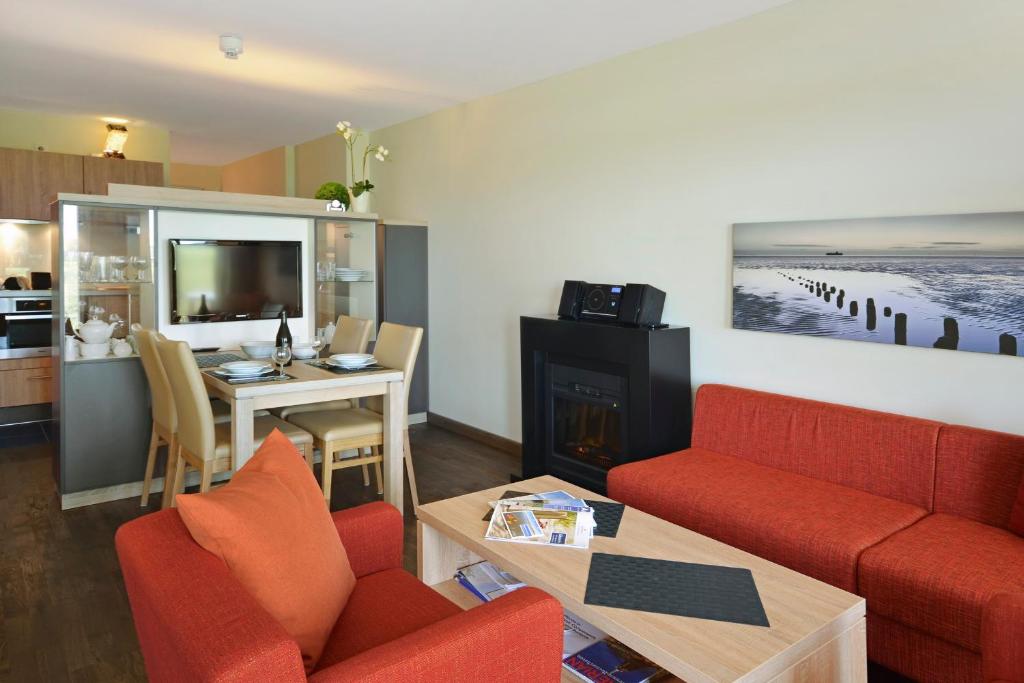 uma sala de estar com um sofá vermelho e uma mesa em Resort Deichgraf Resort Deichgraf 31-03 em Wremen