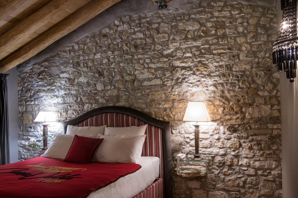 1 dormitorio con pared de piedra, 1 cama y 2 lámparas en Casa Valdo Country House, en Valdobbiadene