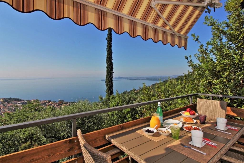 una mesa con comida en el balcón con vistas al océano en Oriolo, en Toscolano Maderno