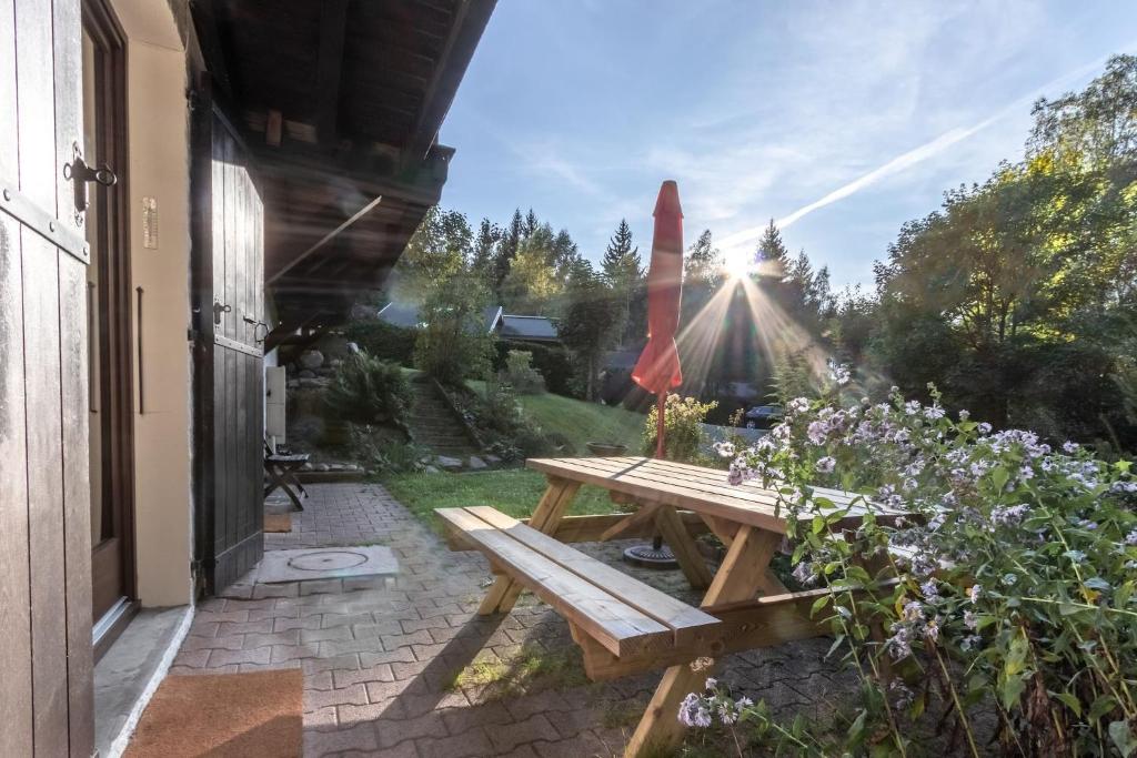 una mesa de picnic de madera en un patio con luz solar en Clos de l'Ours - 2 chambres - Jardin privé en Chamonix-Mont-Blanc