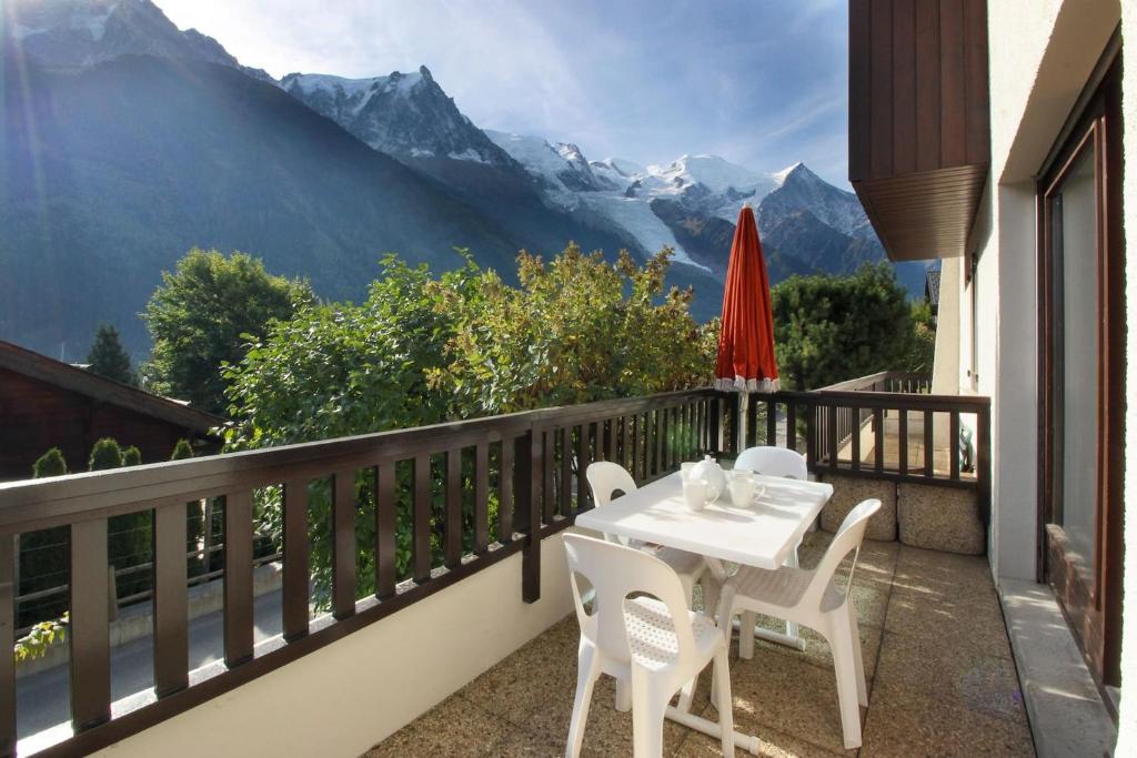 d'une table et de chaises sur un balcon avec vue sur les montagnes. dans l'établissement Les Terrasses de Planpraz - 8min Walk to Center - Quiet - Perfect for Hiking, à Chamonix-Mont-Blanc