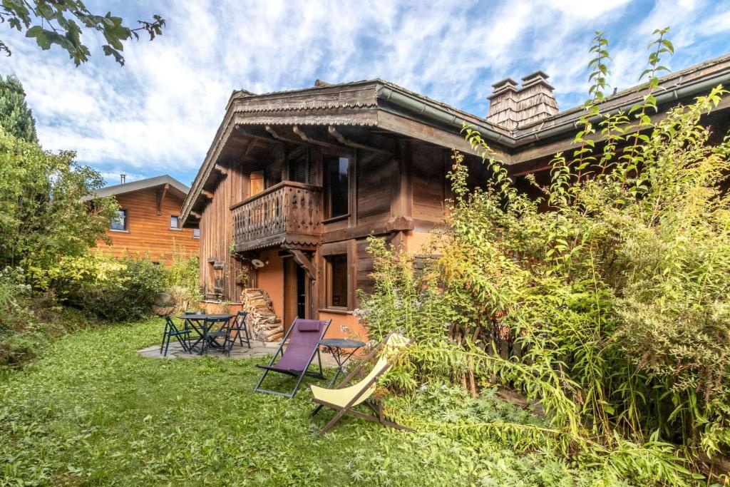 a log house with a deck and chairs in the yard at Les Cristalliers - Cozy family chalet - Close to the village in Les Houches