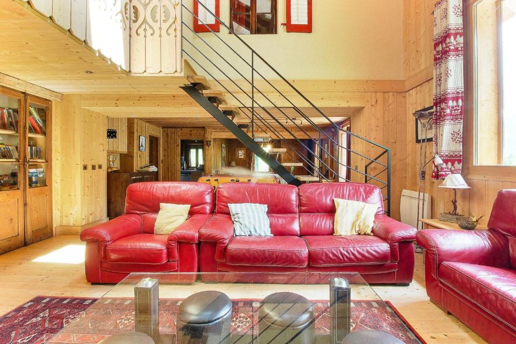 ein rotes Ledersofa im Wohnzimmer mit einer Treppe in der Unterkunft Le Chalet des Chavants - 8ch - 300m2- Grand Jardin - Vues du Mont-Blanc in Les Houches