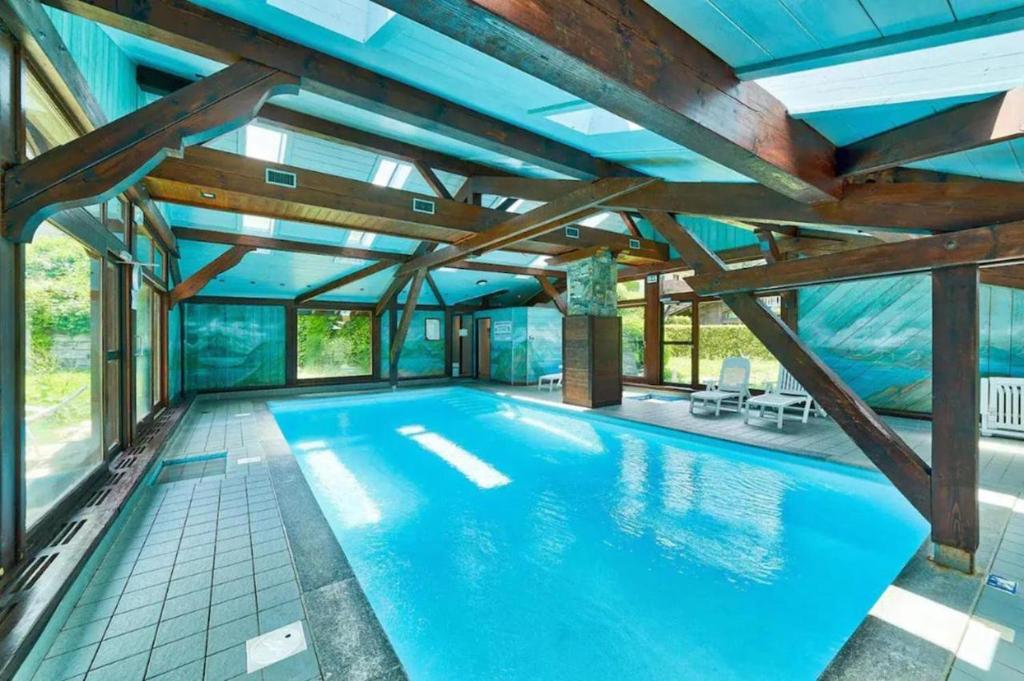 une piscine intérieure avec un plafond aux poutres apparentes dans l'établissement Le Goûter - Ski-in ski-out - Indoor Pool, aux Houches