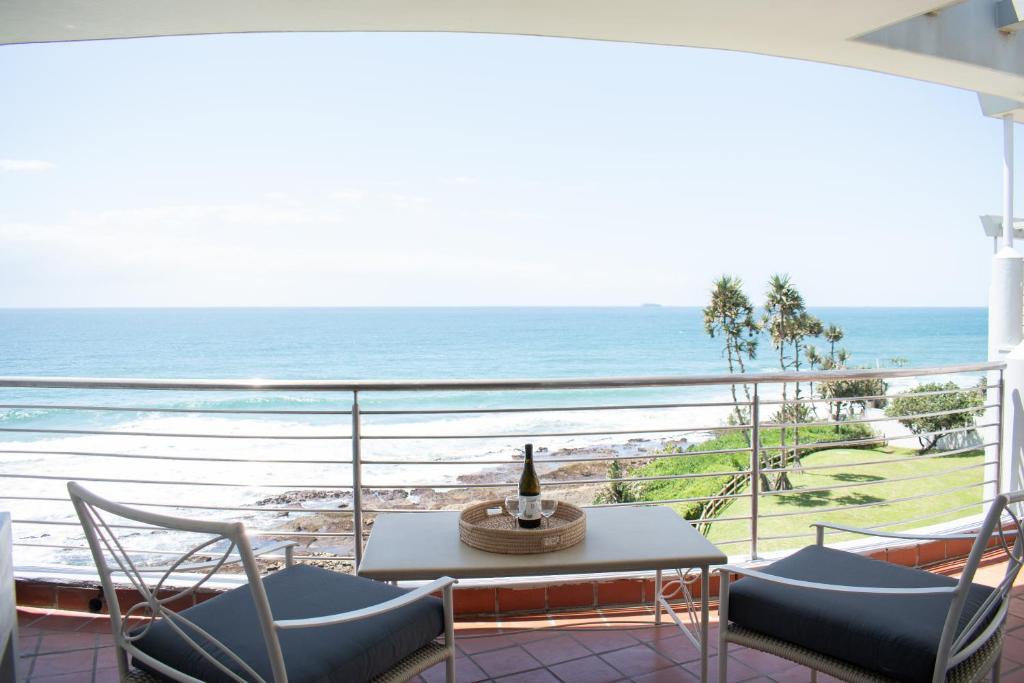 a balcony with a table and chairs and the ocean at Palm Cove - 52 Chakas Cove, Penthouse-Literally on the Beach in Ballito
