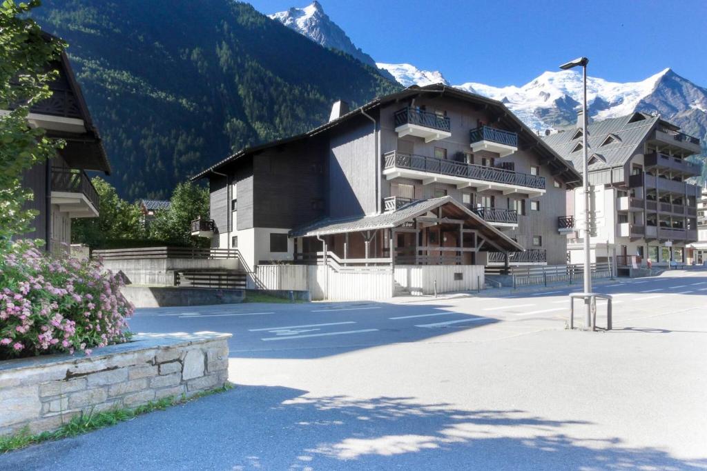 un grand bâtiment avec des montagnes en arrière-plan dans l'établissement Chemin du Sapi - Private Garden - Center of Cham - MontBlanc Views, à Chamonix-Mont-Blanc