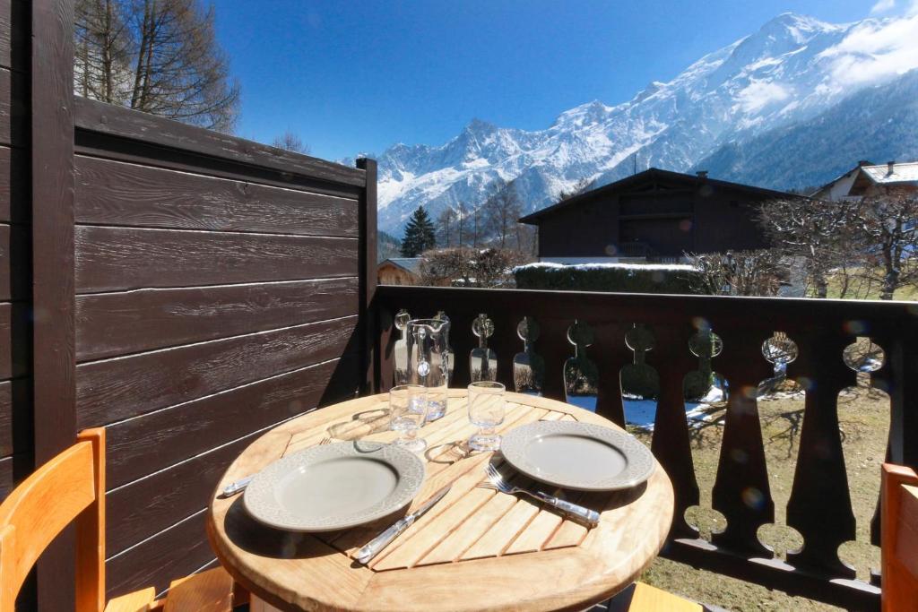 a wooden table with plates and glasses on a balcony at Chalet Charousse in Les Houches