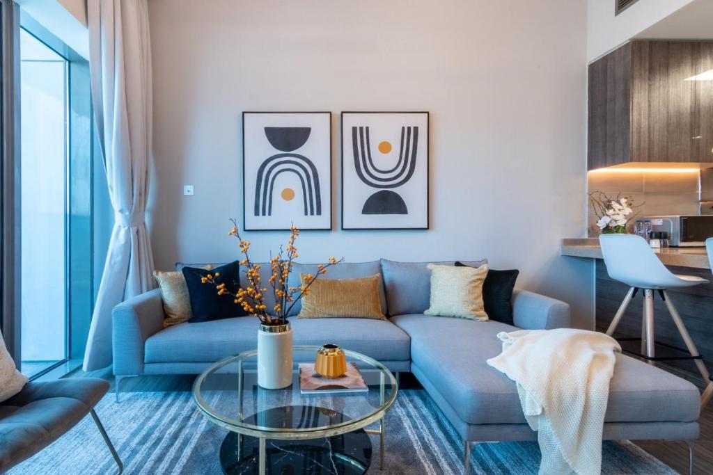 a living room with a blue couch and a glass table at GuestReady - Gray Cloud Lullaby - MBL Cluster in Dubai