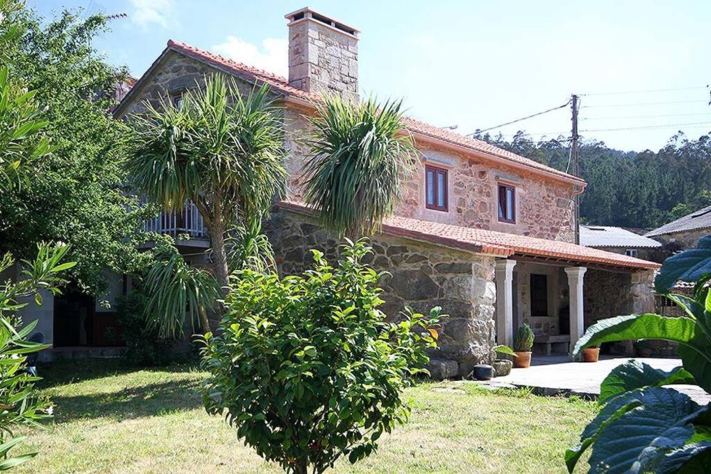 una casa in pietra con palme di fronte di Casa Agrelo Ria de Noia 