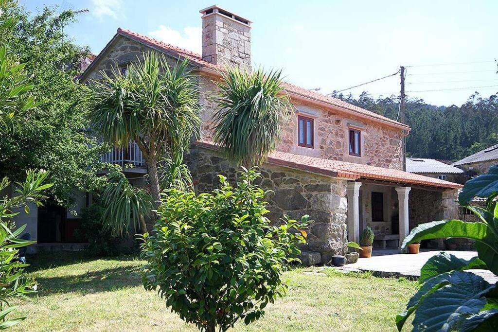 a stone house with palm trees in front of it at Casa Agrelo Ria de Noia in Argellas